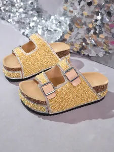 Close-up of glamorous double buckle platform sandals with yellow pearls and rhinestones.