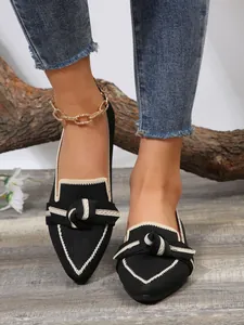 Detail view of stylish black flyknit pointed-toe flats featuring a beige decorative bow