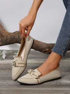 Detailed view of beige knitted loafers with pointed toe and bow knot decoration