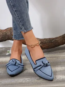 Close-up of blue flyknit flat loafers with decorative bow and dark blue trim