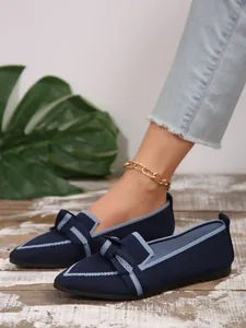 Close-up of navy blue fly-knit pointed-toe flats with light blue bow and trim details.