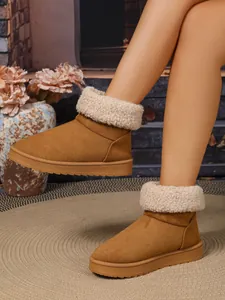 Detailopname van warme bruine damessnowboots met een zachte beige kraag van imitatiebont