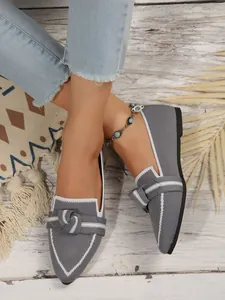 Close-up shot of elegant grey fly-knit loafers with bow detail on model's feet