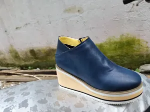 Detailed side view of navy blue wedge bootie highlighting the layered platform sole