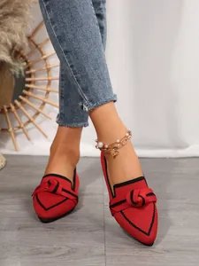 Close-up detail of red knitted pointed-toe flats featuring a decorative bow on the vamp