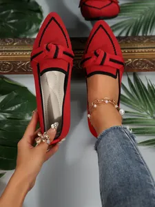 Detailed view of elegant red knitted pointed-toe flat loafers with black bow detail