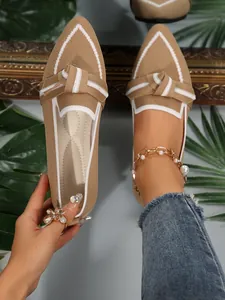 Close-up detail of khaki knitted pointed-toe flat shoes featuring white bow accents