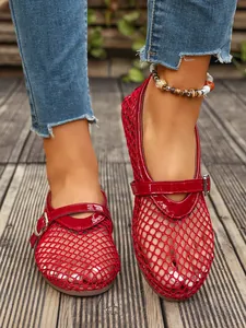 Gros plan sur des ballerines Mary Jane rouges en maille respirante sur fond de terrasse.