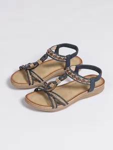Detail view of Bohemian flat sandals featuring ethnic beaded straps and braided rope.
