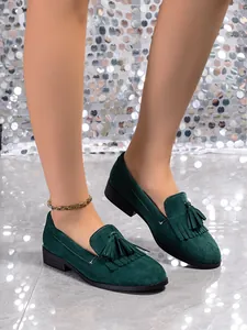 Detail view of dark green suede loafers with elegant tassels and a retro round toe design