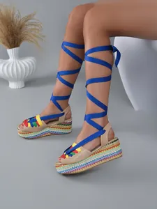Detailed side view of rainbow espadrille platform sandals with blue ankle wrap laces.