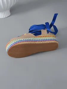 Detailed macro view of the rainbow braided platform sole and vibrant blue ribbons