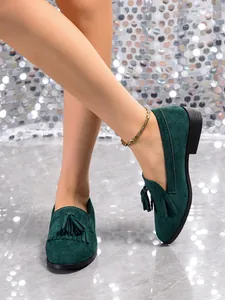 Detail shot of vintage green suede loafers with tassels and soft flat soles for women