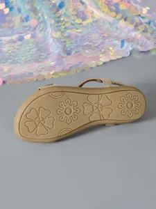 Detailed view of the durable non-slip rubber sole on flat sandals with flower art.