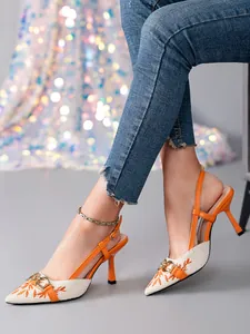 Close-up of orange slingback kitten heels with embroidered pattern and metal buckle