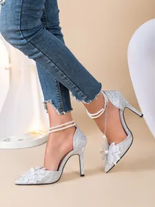 Détail de chaussures à talons hauts argentées avec nœud et bride perles cheville