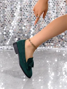 Close-up of green suede loafers with elegant tassel detail and round toe design