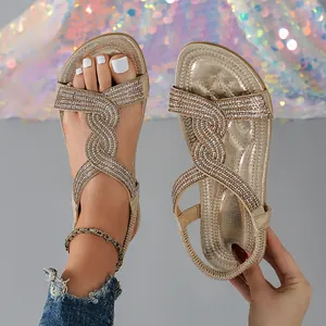 Close-up view of champagne gold flat sandals with sparkling rhinestone cross straps