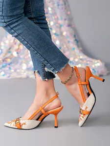 Close-up of elegant orange slingback kitten heels with patterned embroidery and metal buckle