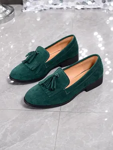 Detailed view of dark green suede loafers featuring classic front tassels
