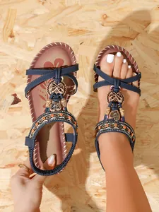 Close-up of Bohemian flat sandals featuring navy blue straps with rhinestone flower accents.