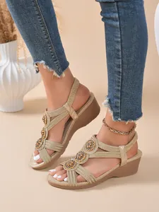 Close-up detail of golden bohemian wedge sandals featuring ethnic decorative ornaments