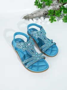 Macro detail of blue Bohemian flat sandals featuring intricate rhinestone floral patterns and gems