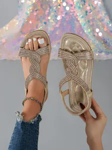 Detailed close-up of shiny gold rhinestone flat sandals for summer beach wear