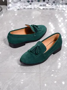 Detail view of dark green suede loafers with vintage fringe and tassel design
