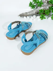 Detail view of blue bohemian flat sandals with rhinestone straps and elastic heel