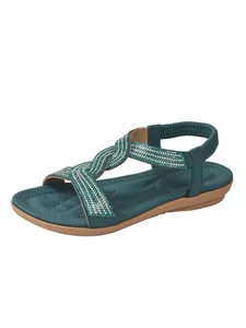 Detailed view of green women's flat sandals with sparkling rhinestone straps