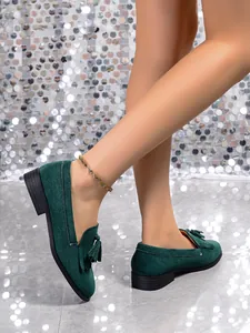Close-up of dark green suede loafers with stylish tassels and vintage round toe on model