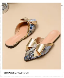 Gedetailleerde weergave van platte slippers met puntneus, gouden strik en strass-steentjes
