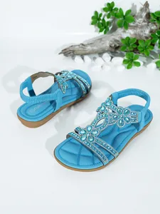 Detailed close-up of blue Bohemian flat sandals featuring intricate rhinestone flower patterns