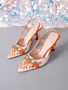 Detail view of orange slingback pumps featuring floral embroidery and gold horsebit buckle