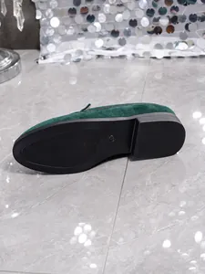 Detail of non-slip rubber sole on dark green suede loafer showing the grip pattern