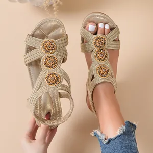 Close-up of women's champagne gold wedge sandals with braided straps and floral rhinestone details