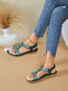 Close-up shot of stylish teal flat sandals featuring intricate rhinestone strap details