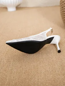 Close-up of white floral lace pointed-toe slingback heels with anti-slip rubber sole.