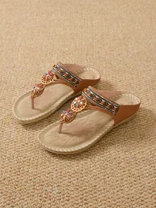 Detailed view of bohemian flat sandals with rhinestone floral and bead embellishments.