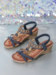 Detailed view of bohemian wedge sandals with intricate hand-beading and butterfly motifs.