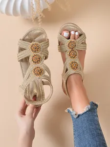 Detail view of gold wedge sandals with elegant circular floral crystal embellishments