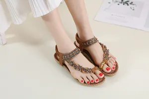 Detailed macro view of Bohemian brown flat sandals featuring intricate beadwork and butterfly charms