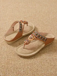 Detailed view of bohemian flip-flop sandals with rhinestone flowers and ethnic straps.