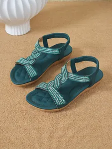 Detailed view of teal flat sandals featuring elegant rhinestone-encrusted crisscross straps.