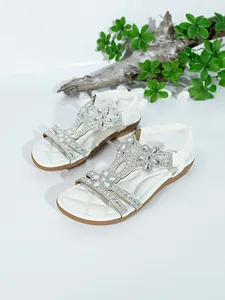 Elegant white flat sandals with sparkling rhinestone flowers on a clean background