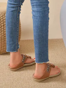 Detailed close-up view of Bohemian flat sandals with rhinestone flowers on feet