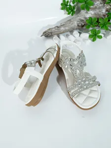 Detailed view of white bohemian flat sandals with sparkling rhinestone embellishments