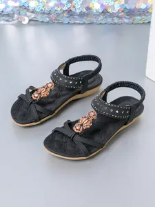 Detail view of black bohemian flat sandals with beaded flowers and sparkling rhinestones