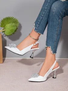 Detailansicht eleganter weißer Slingback-Heels mit Krokoprägung und funkelnder Strassblume